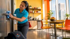 Woman cleaning office door handle