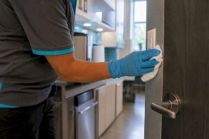 Gloved hands disinfecting door handle