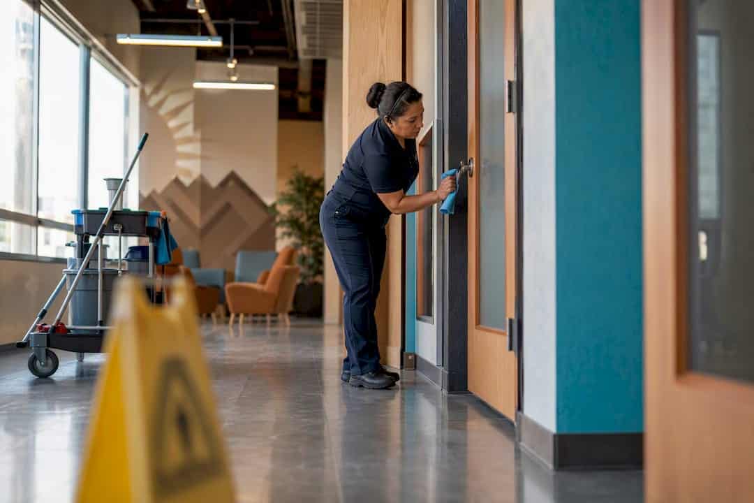 Janitor wiping office door handle