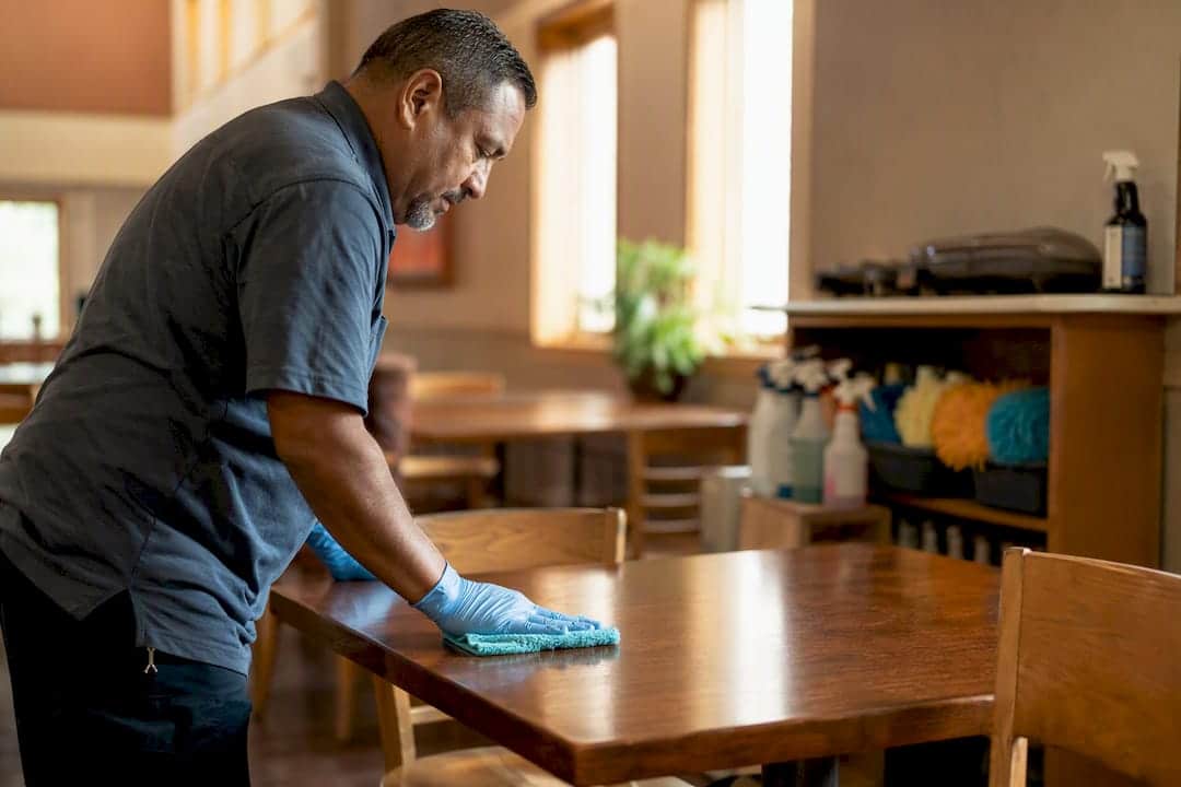 Volunteer wiping church wooden pew