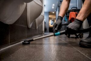 Technician extracting odor from restroom grout